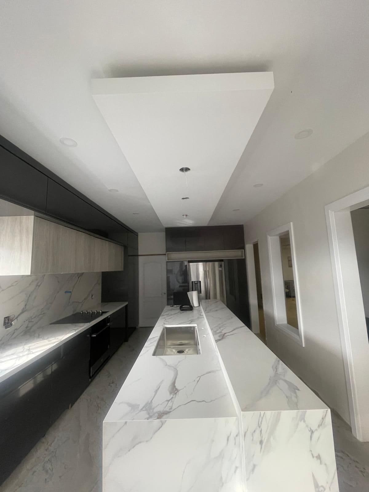 Finished kitchen with dark cabinets and a white marble waterfall island, renovation in Brampton