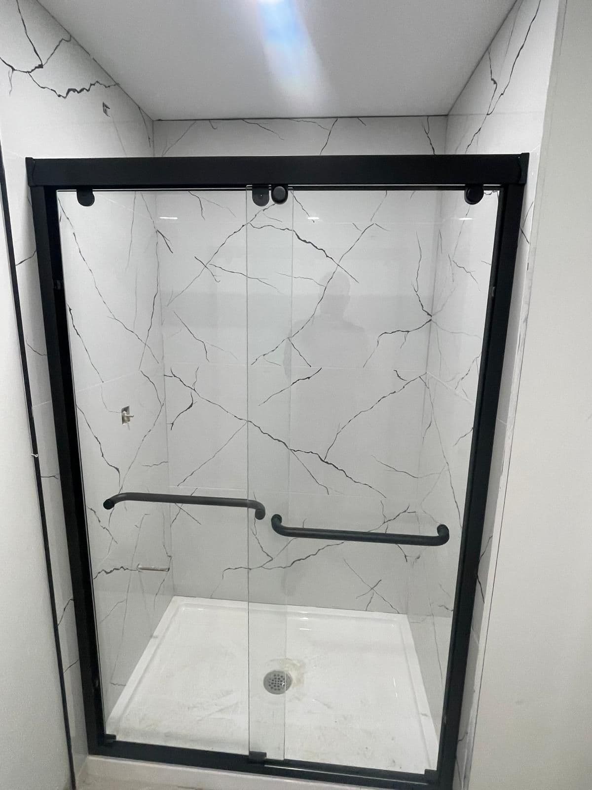 Black-frame bypass glass shower doors on a tiled shower, bathroom renovation in Brampton